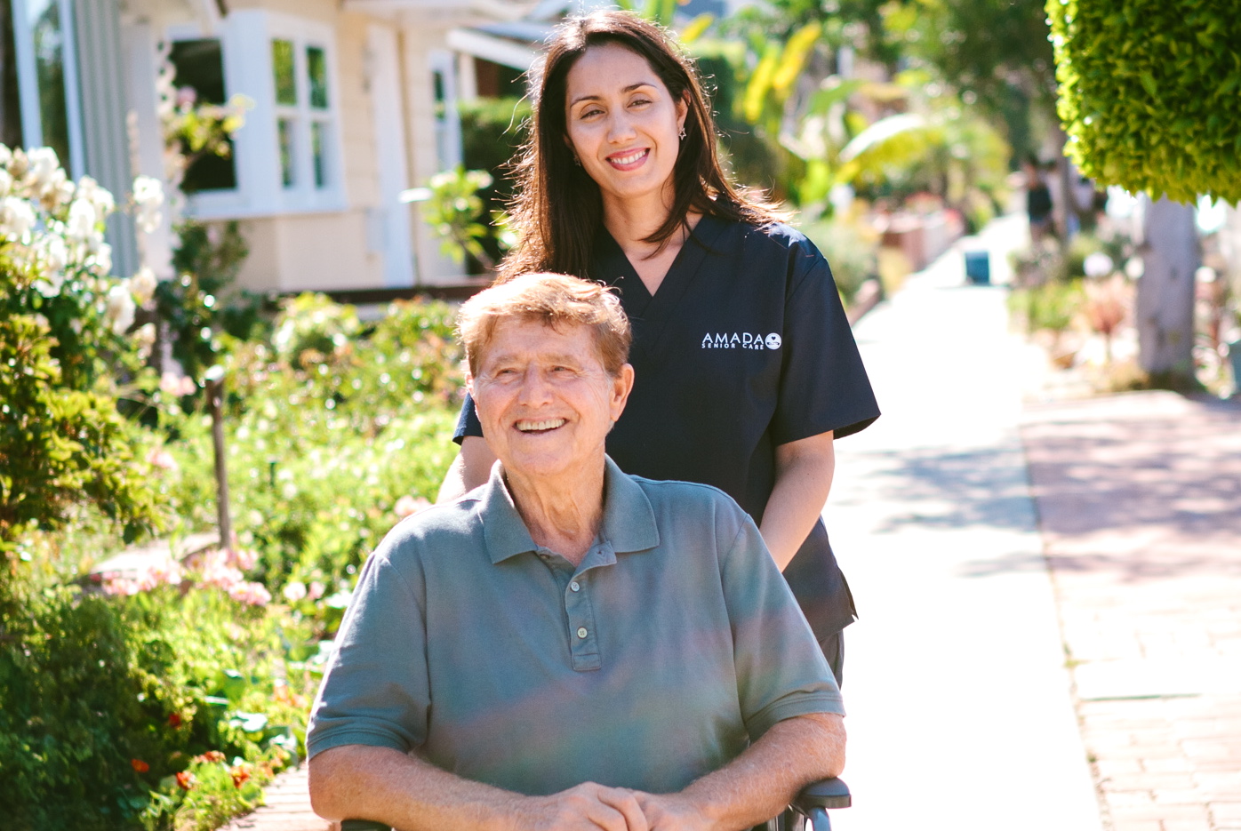 1569 An Amada caregiver assists an elderly man on the sidewalk.